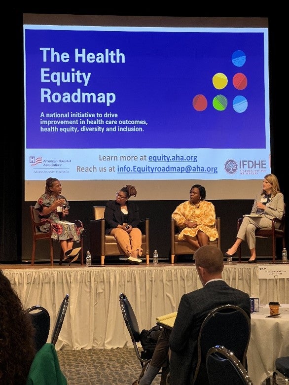 Panelists sit on stage in front discussion the Health Equity Roadmap