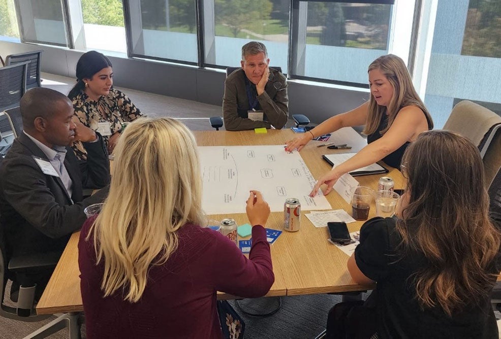 Participants in Region 8 Summit sit around a table making notes and discussing ideas