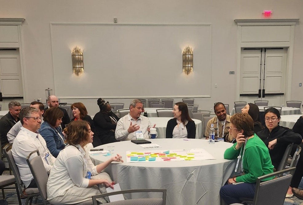 Rural Summit attendees sit arouns a table in a hotel conference room